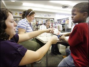 Slug: NBRN music13p Date:  11/04/2008        The Blade/Andy Morrison       Location:   Monroe  Caption: Branch librarian Amber Reed helps Daniel Robertson and other children make shekeres, a Nigerian instrument, as part of Musical Instruments Around the World program at L.S. Navarre Library Branch in Monroe, Wednesday, 11/05/2008. Summary:
