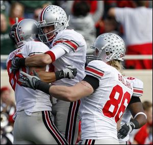 Brian Robiskie, left, is congratulated by Brian Hartline, center, and Jake Ballard after catching a TD pass for OSU. A win over Michigan would give OSU a share of the Big Ten title.