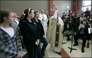 Bishop Leonard Blair blesses the Blessed John XXIII Parish Life Center on Dixie Highway in Perrysburg as, from left, Alexa Long, Stephanie Richards, and Hailey Oeder, all 14, watch.