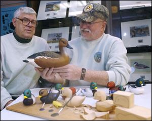 Charlie Hill and Jim Manning inspect wooden duck carvings at the Wooden Feather Day at Magee Marsh State Wildlife Area in Ottawa County. Three members of the Maumee Bay Carvers group displayed their carvings and each was honored as a winner. Wooden Feather Day has been an annual tradition for 15 years at Magee Marsh, but rain led to a smaller turnout yesterday.