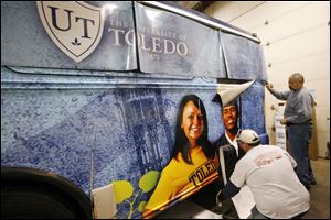 Chuck Bolt and Jerry Templeton, both of Columbus, wrap up work on a University of Toledo bus before it heads to a Cleveland high school.