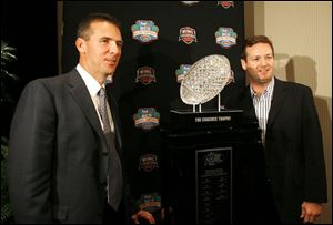 Florida coach Urban Meyer, left, and Oklahoma s Bob Stoops spent yesterday shaking hands for photographers. One of the coaches will be photographed beside the trophy on Jan. 8.
