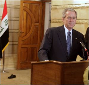 A shoe hurled by a reporter at a news conference in Baghdad on Sunday lies on the floor behind President Bush, the intended target.