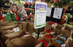 At left, Dawn Miller and her daughter Claire, 6, pick out a  Help Us Help  bag to purchase at The Andersons store on Talmadge Road. 