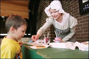 Janet Rasmussen adds sprinkles to a Christmas cookie for Jacob Sullivan of Oregon at the Fort Meigs Holiday Open House Sunday.