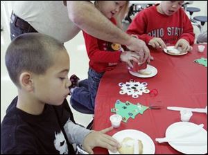 NBRS santa18p  12_13_2008      Blade Photo_Lori King  kids from left: Springfield Township residents Logan Spangler, 7, Camryn Miller, 4 and Trevor Spangler, 10, decorate cookies with their grandfather, Stanley Spangler, of Rossford, during Breakfast with Santa at Springfield HS in Holland, OH.
