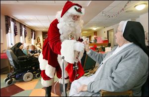 Sister Jean Francis Boes, right, gets a treat from Santa, aka Tim Stapleton, during his annual visit to the sisters  convent.