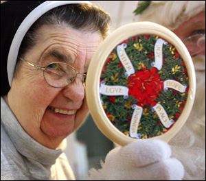 Sister Mary Carola Billat peeks into Santa s magic mirror to see if she s been good and eligible for a treat. Tim Stapleton estimates he makes 200 annual appearances in his Santa garb.
