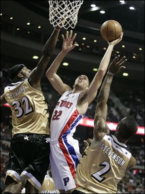 The Pistons' Tayshaun Prince scores as the Wizards' DeShawn Stevenson, right, and Andray Blatche try to deny his attempt.