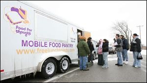 Jeanette Hrovatich of the United Way and Don Schiewer of Food for Thought register individuals for the food-mobile s recent visit to South Toledo s Aurora Gonzalez Community Center.