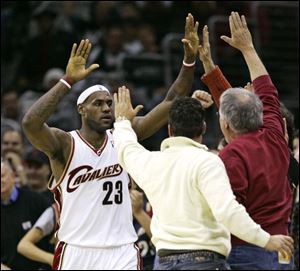 Cleveland s LeBron James high-fives a pair of Cavaliers fans. James finished with 27 points, 18 in the second half.
