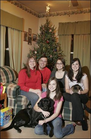 Allan Murphy is surrounded by his wife, Kathy, left, and daughters Brianna, Erin, holding Lillian the cat, and Allison, on the floor with their black Labrador, Ember.