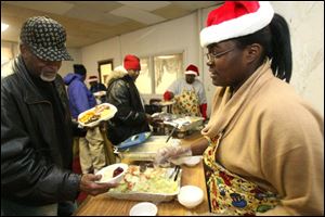 Disha Brooks serves salad to Mike Mickles at Thomas Temple Church of God in Christ. This is the fourth year for the church's holiday meal. 