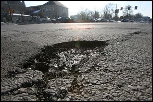 One of the city's large potholes is located on the corner of West Bancroft Street and North Detroit Avenue.