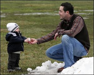 Jeff Kryspin of Whitehouse and his son Ian, 18 months, play in the snow. Or play in what's left of it. True, they could have made snowballs last week, when the ground was white, not green, brown, and waterlogged. But, Mr. Kryspin said, it was just too doggone cold back then.