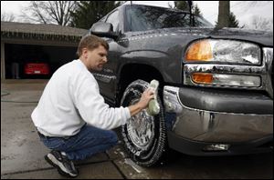 Tom Rahman takes advantage of a 60-plus degree day to rid his sport utility vehicle of all traces of salt and snow in the drive of his Maumee home. 