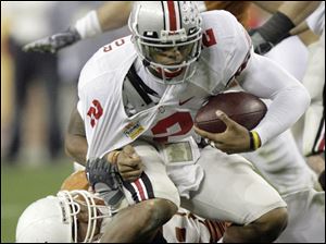 Ohio State quarterback Terrelle Pryor is sacked by Texas tackle Roy Miller.