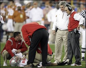 Ohio State coach Jim Tressel, right, and Texas coach Mack Brown watch medical personnel work on Shaun Lane.