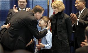 Richard Cordray seals his oath to become Ohio's attorney general with a kiss to his son Danny, as his wife, Peggy, and David Pepper, master of ceremonies, look on.
