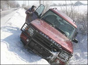 Joe Crapsey helps Fatima Hashmi after her Land Rover slipped into a ditch on Roachton Road in Perrysburg on Thursday.