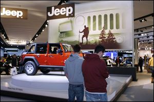 Michael Lotz, left, and Seth Myers inspect the Jeep Rubicon at the Detroit auto show, which opened to the public yesterday.