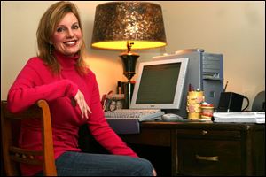 Michele Howe works in the office of her Michigan home. At right are some of her books.