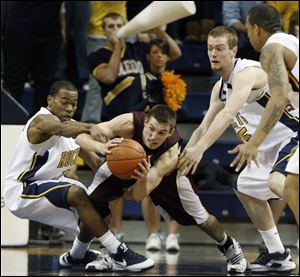 With Ian Salter applying pressure, Toledo guard Larry Bastfield, left, reaches for the ball but winds up grabbing the arm of Central Michigan s Robbie Harmon last night at Savage Arena.