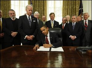President Obama signs an executive order closing the prison at Guantanamo Bay on Thursday in the Oval Office of the White House in Washington.