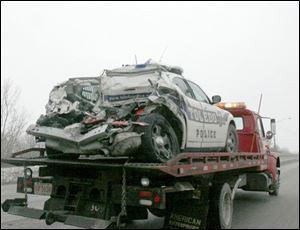 A police car is towed down Alexis Road after an early morning crash on north I-75. Officers Michael Haynes, 34, and James Taylor, 37, were treated at St. Vincent Mercy Medical Center and released. The Tennessee truck driver also was treated there.