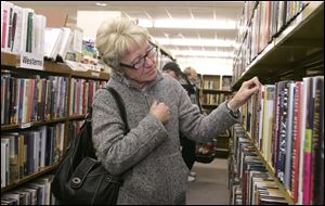 CSue Fesenmyer of Holland combs the shelves for a good buy. The sale continues from 9 a.m. to 4 p.m. today and tomorrow at the Book Center, which is in the Reynolds Corners Shopping Center on the southwest corner of Dorr Street and Reynolds Road.