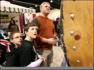 Joshua Swartz, left, his brother Parker, center, and their dad, Pete, watch a spinning wheel to see if they won a prize. Yesterday was the last day of the show. It opened Friday.