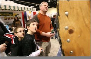 Joshua Swartz, left, his brother Parker, center, and their dad, Pete, watch a spinning wheel to see if they won a prize. Yesterday was the last day of the show. It opened Friday.