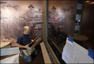 With a photo of a Civil War battlefield in the background, Steve Pistolessi installs part of the Lincoln Bicentennial exhibit that is to start Thursday and run through May.