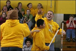 Teacher John Kidd gives a high-five to Angelo Flores, who just made a goal during a hockey shootout.