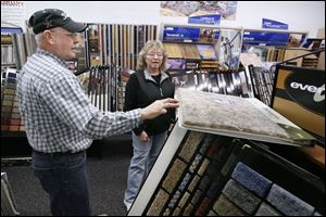 Jack Lynch, showing Sharon Supinski samples at his Carpet Source Plus store in Northwood, says sales are down about 50 percent in the last two years, but the family-owned company has been able to cope.