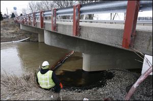 A worker from EQ Industrial Services monitors the pumping of oil from Rocky Ford Creek at Cygnet Road in Cygnet, Ohio. A leak in a pipeline, discovered Wednesday, let thousands of gallons flow into the creek, then into the Portage River. Crews were to vacuum the oil around the clock until the job is completed.