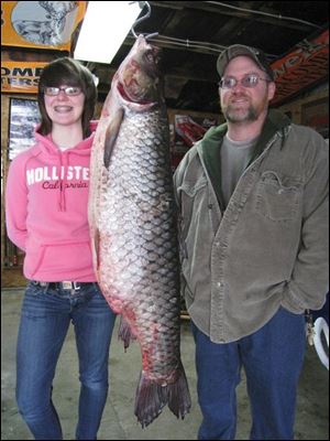 Ron Davenport of Fremont, right, poses with his daughter, Emily, and a 53-pound white amur that turned up in his backyard.