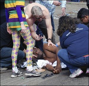 An unidentified shooting victim is aided after gunfire broke out following the last major parade of New Orleans' Mardi Gras. Seven people were injured and two men were taken into custody.
