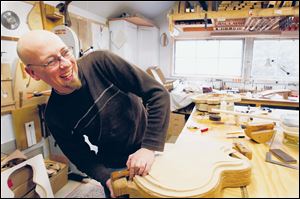 Denny Kopp clamps a guitar top before carving it in his shop.