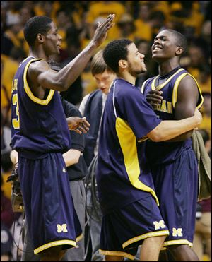 Michigan's Manny Harris, left, David Merritt, center, and Laval Lucas-Perry celebrate the Wolverines' victory over Minnesota.