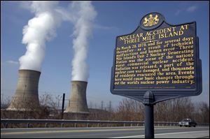 A historic marker stands near the Three Mile Island Unit 2 reactor, site of the March 28, 1979, nuclear accident, as steam pours from the cooling towers of the TMI Unit 1 plant on a recent day.