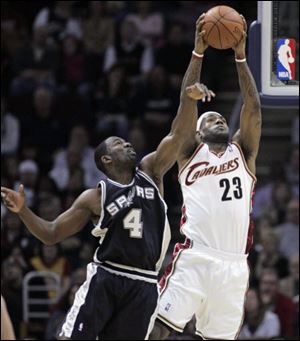 The Cavaliers' LeBron James catches a pass from a teammate under pressure from the Spurs' Michael Finley in the first quarter Sunday at Quicken Loans Arena in Cleveland. 