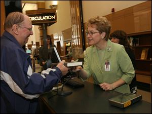Slug: CTY marcy13p                                Date 4/13/2009           The Blade/ Amy E. Voigt                     Location: Toledo, Ohio  Caption: U.S. Rep. Marcy Kaptur (D., Toledo), center, checks out books for George Tucker, left, with the help of library employee Cathy Bartel, right, on April 13, 2009.  Kaptur spent one hour with librarians and clerks to assit patrons with checking out their  materials as part of the library's "very special guest" series.