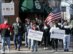 Members of United Auto Workers Local 723 who are laid off from Chrysler LLC s Global Engine Manufacturing Alliance plant in Dundee, Mich., walk through downtown Monroe yesterday to tout how they have received industry accolades for the quality of their product and to urge people to buy American-made products.
