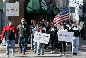 Members of United Auto Workers Local 723 who are laid off from Chrysler LLC s Global Engine Manufacturing Alliance plant in Dundee, Mich., walk through downtown Monroe yesterday to tout how they have received industry accolades for the quality of their product and to urge people to buy American-made products.