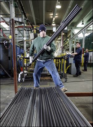 Stiner Wright, an employee of American Posts, stacks heavy-duty steel 'U' fence posts as they come off the line at the small firm. Feniger