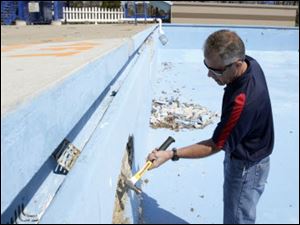 Neal Graf, Wauseon Parks and Recreation director, chips away at the side of the Reighard Park pool. Contractors  estimates for concrete patching and repainting started at $67,000, and that didn t cover plumbing repairs the pool also needed, Mr. Graf said.