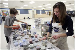 Russell Walters, 14, an eighth grader, picks up supplies as art teacher Shari Densel checks out the cans of paint for students to apply to the mural at Anthony Wayne Junior High School.