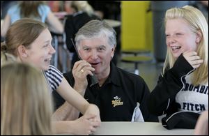 Principal Dale Wiltse answers a call on his radio while talking with students Taylor Monhelm, left, and Miranda Van Hoozen.