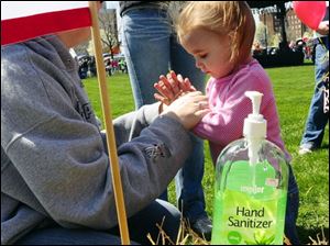 Amanda Scraker, left, sanitizes the hands of her daughter, Sydney, 2, before letting her play at a petting zoo in Holland, Mich. Ms. Scraker is concerned about swine flu.